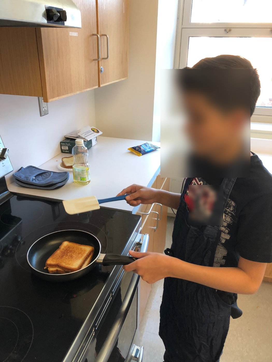 Student flipping a grilled cheese sandwich in a skillet