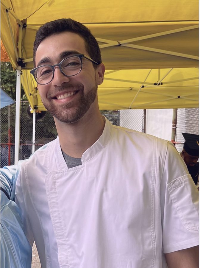 Chef Jeremy Kaplan smiling in his white chef coat at an outdoor cooking event